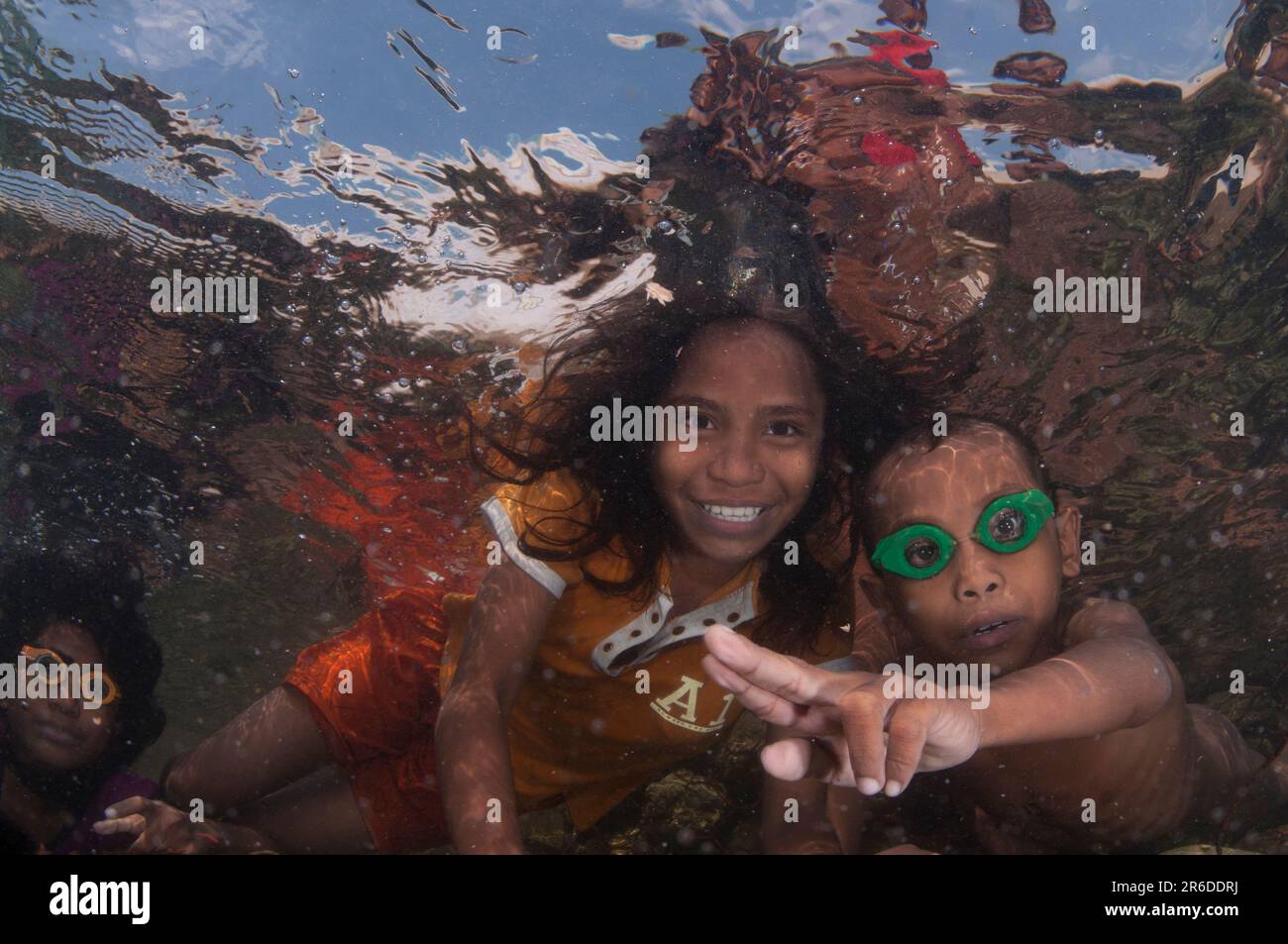 Kids with goggles underwater and making hand signals, Pier, Reta Island ...