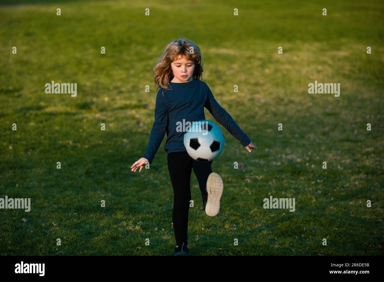 Boy child playing football on football field. Kid playing soccer