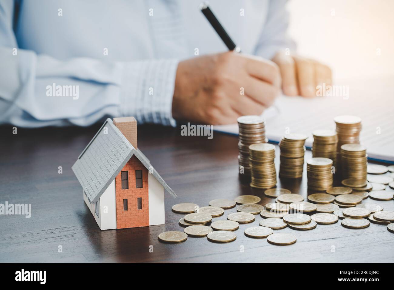 House model with stack coins, business hand is planning savings money of coins for buy home. concept for property ladder, mortgage with real estate in Stock Photo