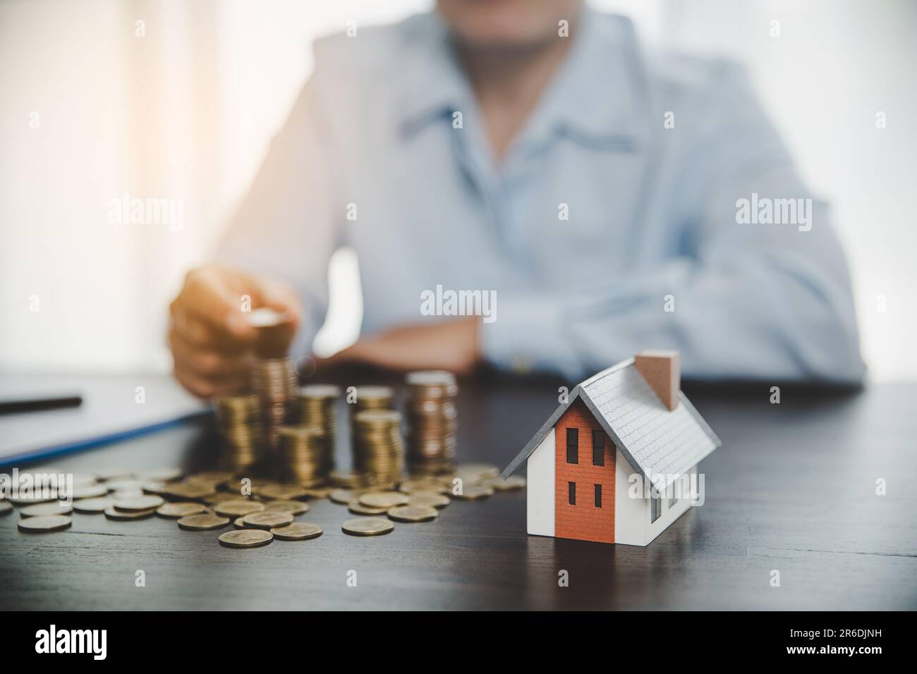 House model with stack coins, business hand is planning savings money of coins for buy home. concept for property ladder, mortgage with real estate in Stock Photo