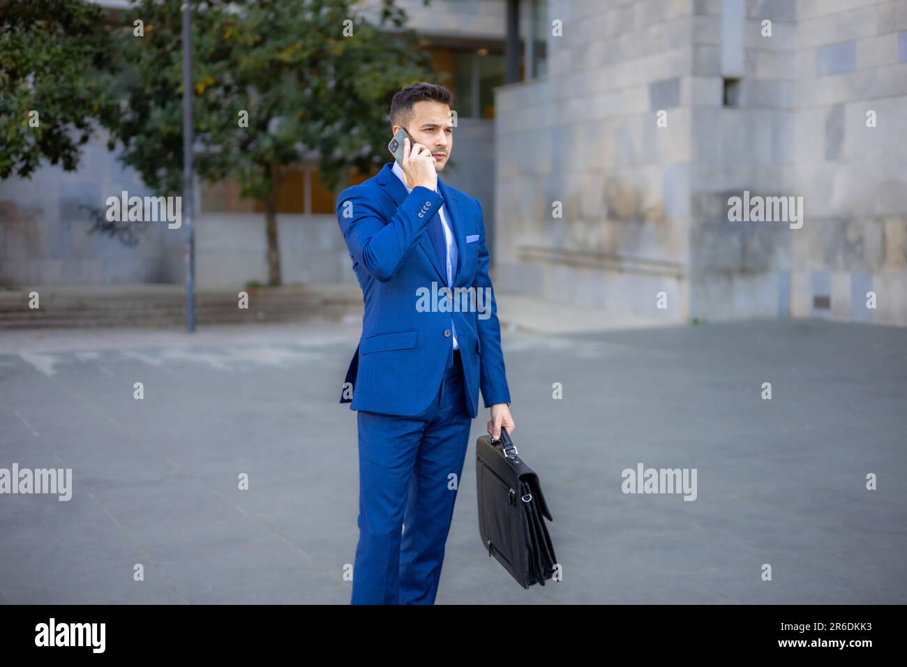 Handsome economist, lawyer, CEO, entrepreneur, executive director and businessman talking with smartphone outside the office. Stock Photo