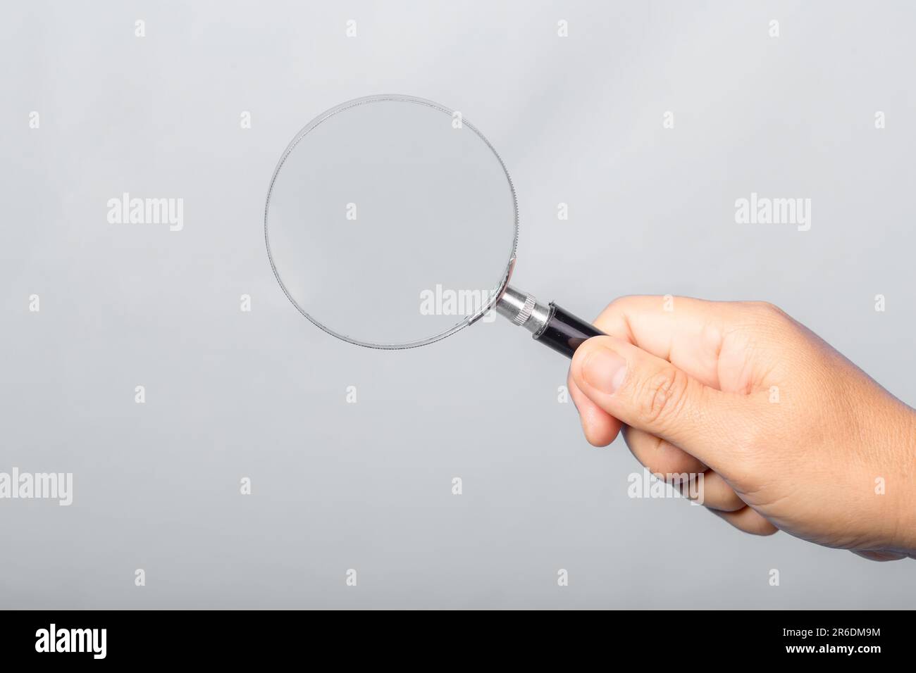woman hand holding magnifying glass isolated on gray background