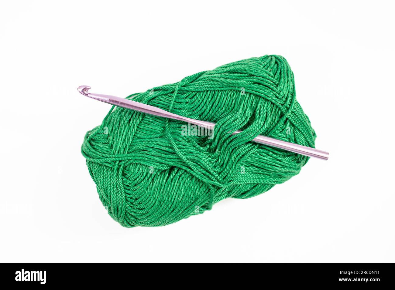 Dark green thread spool with purple crochet hook, isolated on