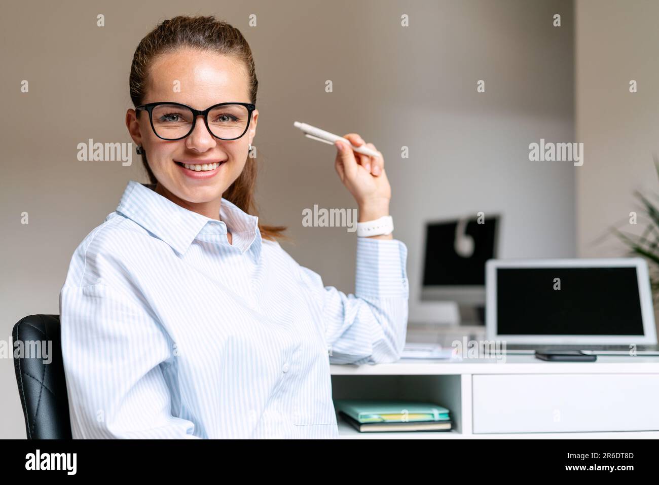 Business woman in glasses smiles and looks at the camera while working at the table in the office. Stock Photo