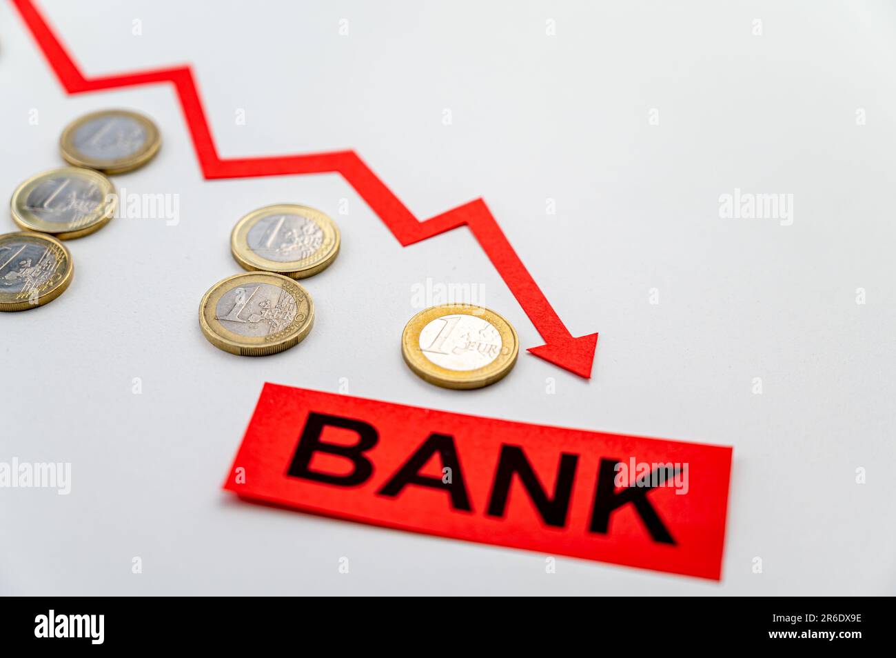 Rows of coins of descending height, descending red line, and the word