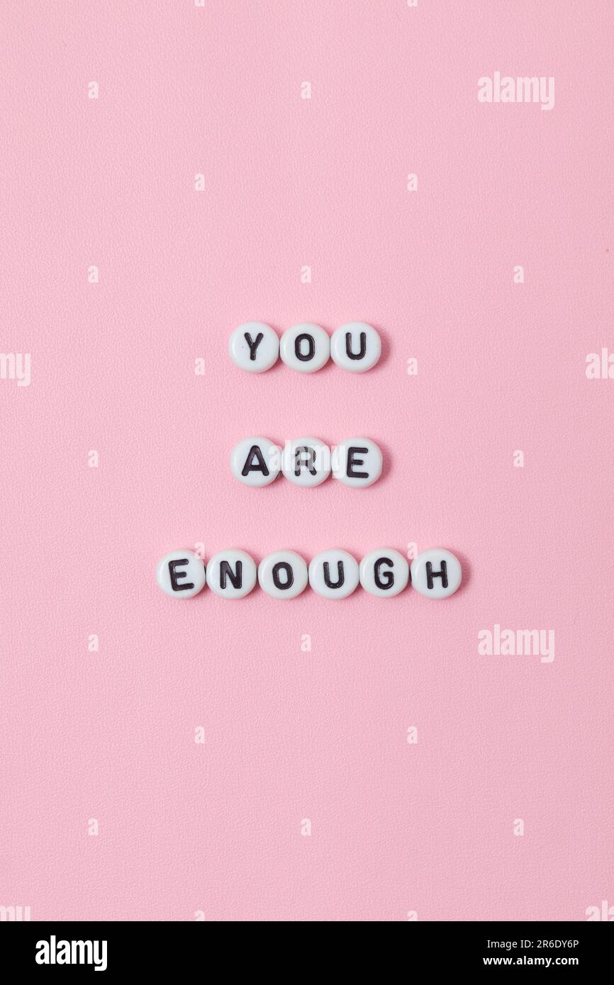 Top view of "you are enough" quotes made out of beads on pastel