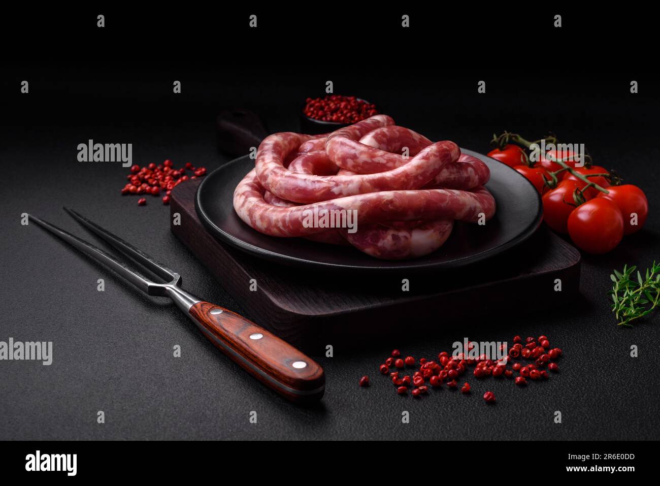 Raw sausages from pork or beef with salt, spices and herbs on a dark