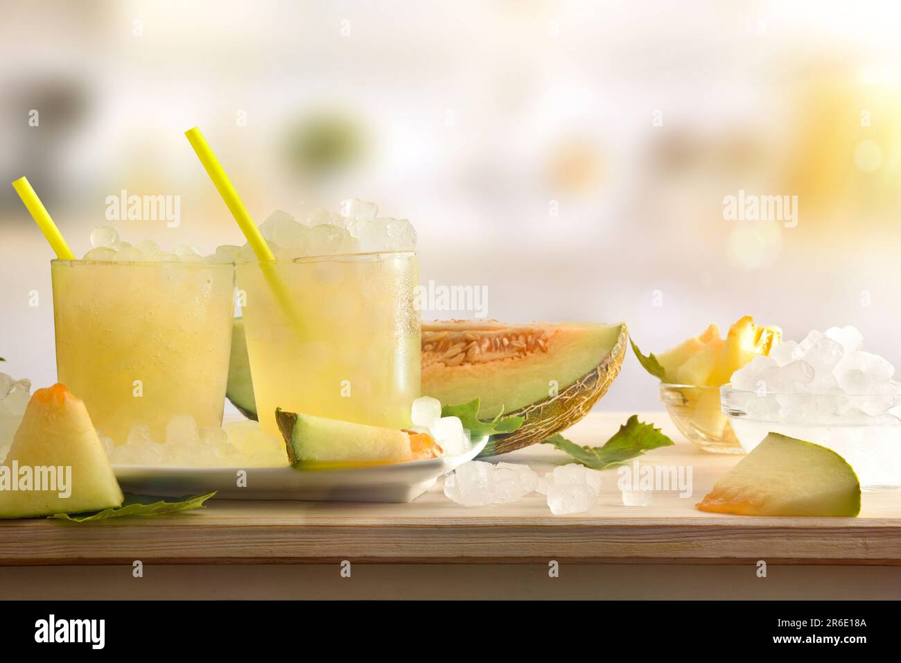 https://c8.alamy.com/comp/2R6E18A/two-glasses-with-iced-melon-drink-on-wooden-table-full-of-crushed-ice-and-sliced-fruit-around-with-kitchen-in-the-background-front-view-horizontal-c-2R6E18A.jpg
