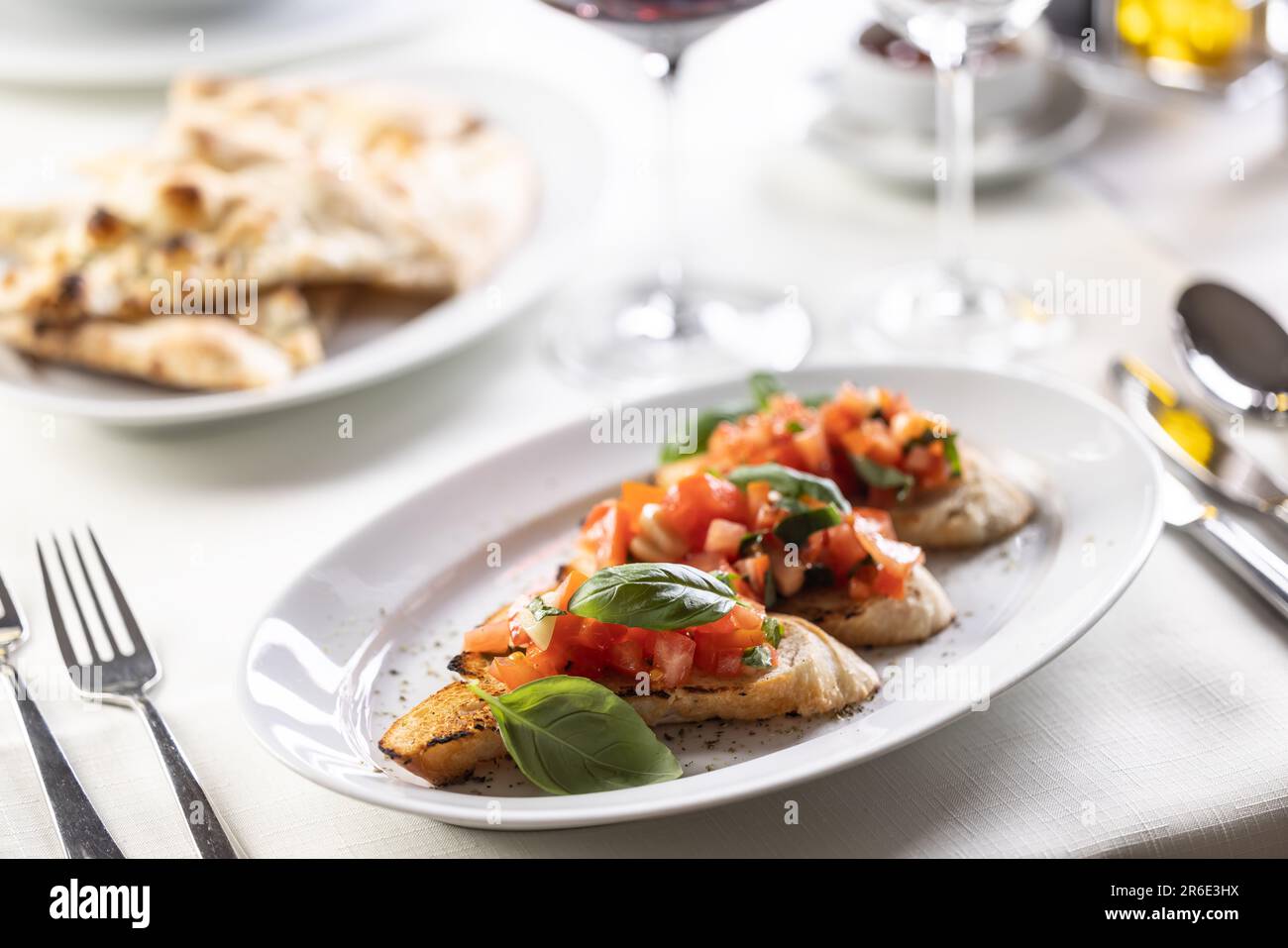 Italian appetizer with three bruschettas topped with tomatoes and greens in a cafeteria. Stock Photo