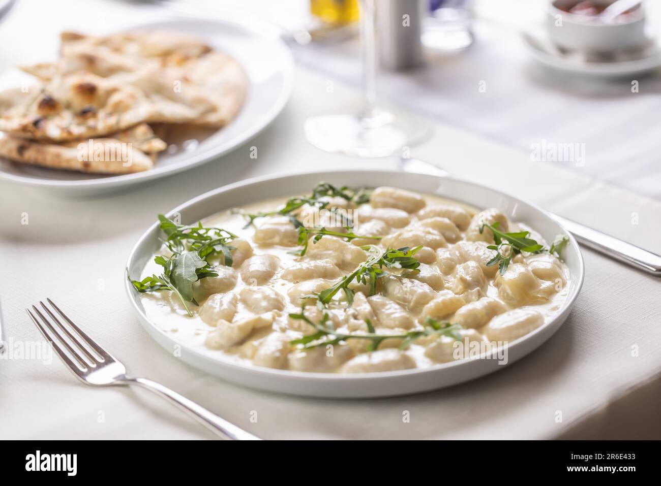 Italian gnocchi ai quatro formaggi with pizza bread on the side served on a table. Stock Photo