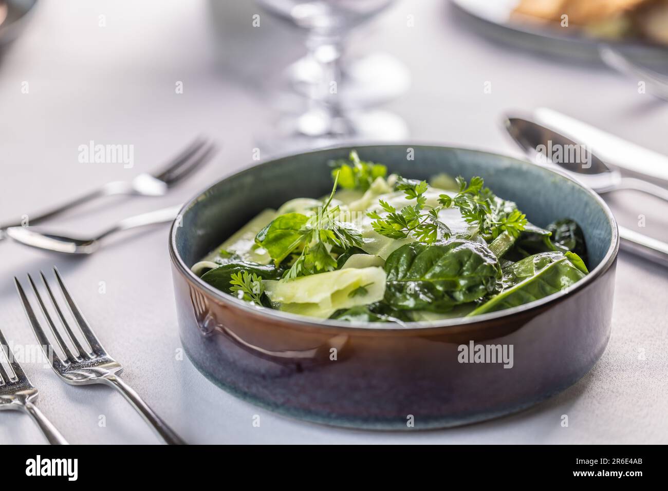 Kohlrabi and spinach leaves salad in a dark bowl in the restaurant. Stock Photo