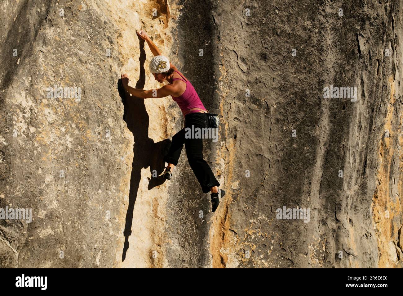 A young woman rock climbs on a streaked wall of limestone, Castle Hill, New Zealand. Stock Photo
