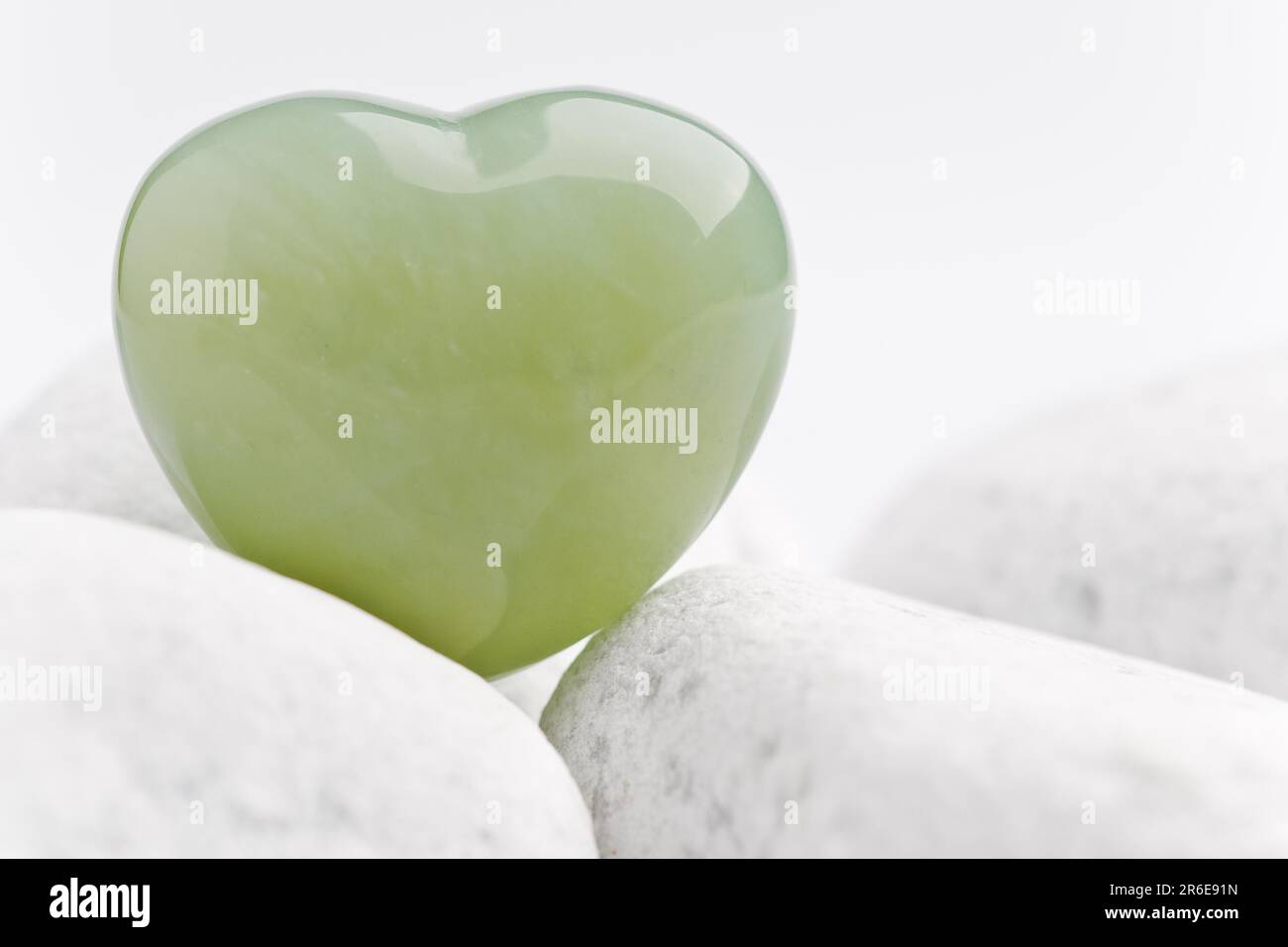 Green quartz mineral heart as symbol of love on white stones Stock