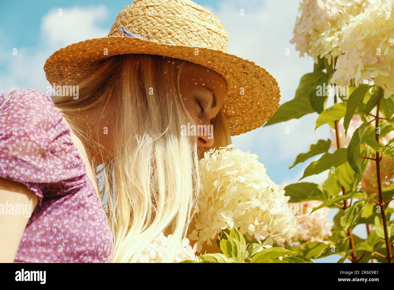 Young blonde woman in a straw hat smell the flowers Stock Photo Alamy