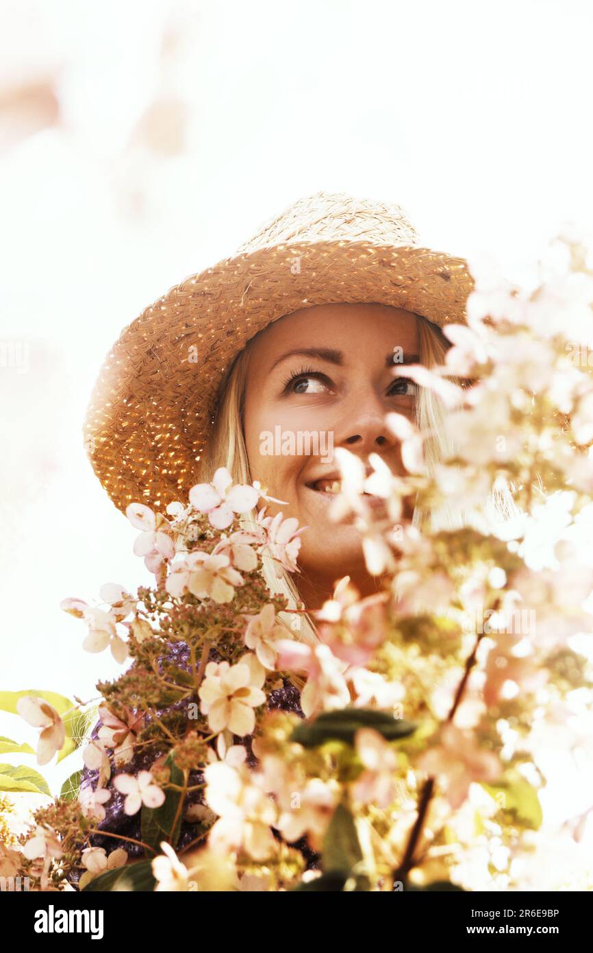 Woman in a straw hat with flowers hi-res stock photography and images ...