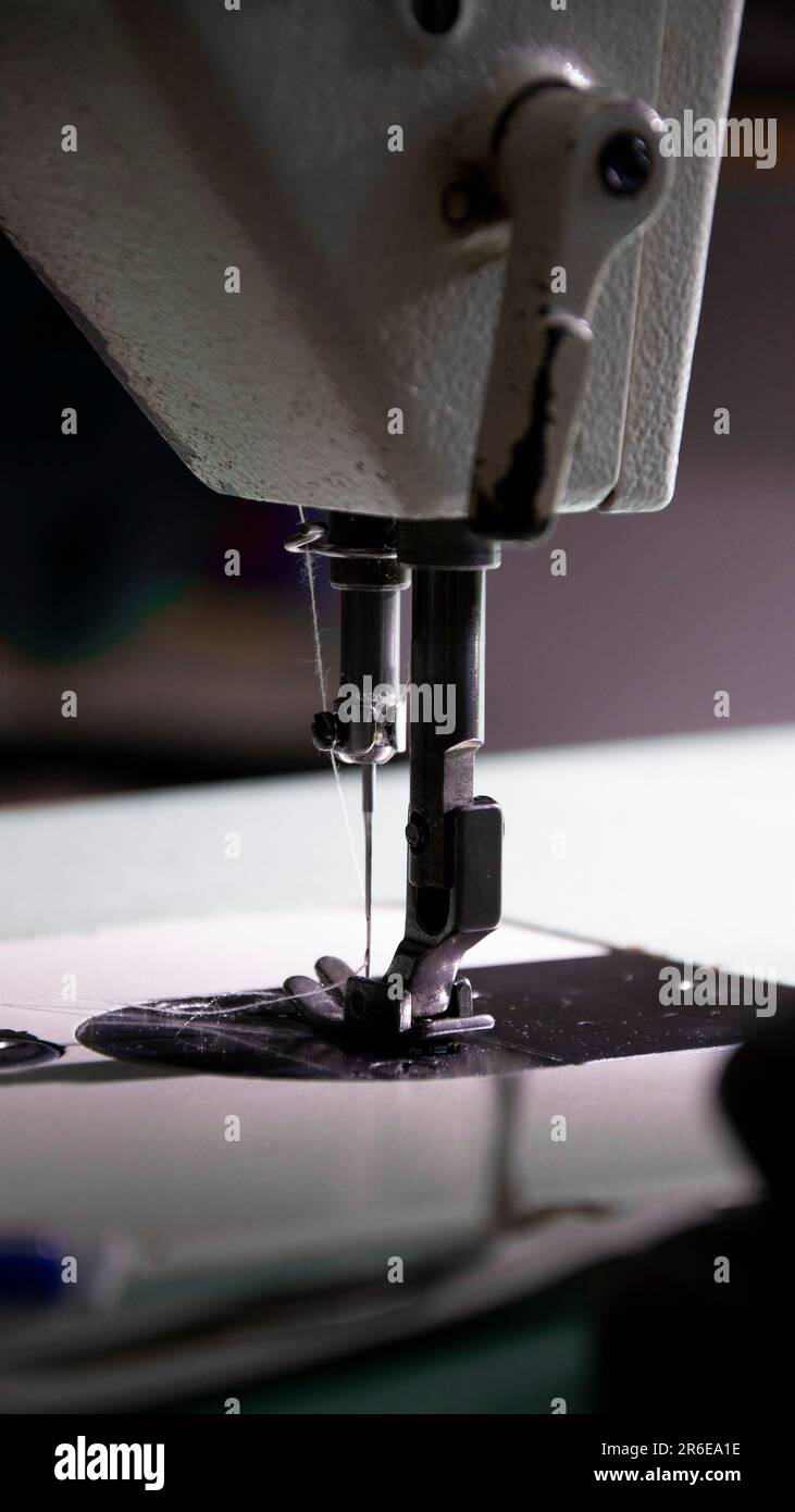 Man's feet at pedal of industrial sewing machine stock photo - OFFSET