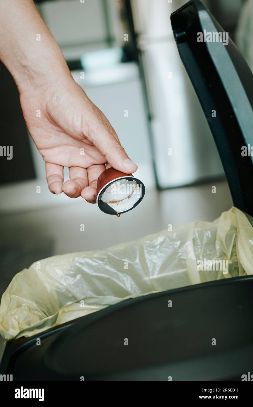 closeup of a caucasian man throwing an emptied coffee capsule to the recyclable waste dustbin in the kitchen Stock Photo