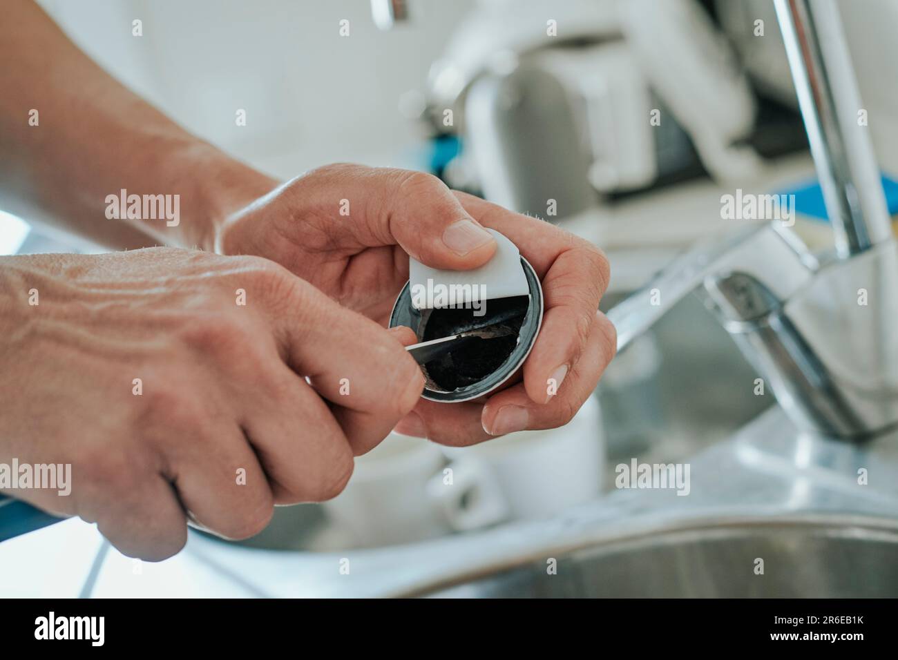 closeup of a caucasian man in the kitchen emptying the used ground coffee of a capsule to recycle the capsule Stock Photo