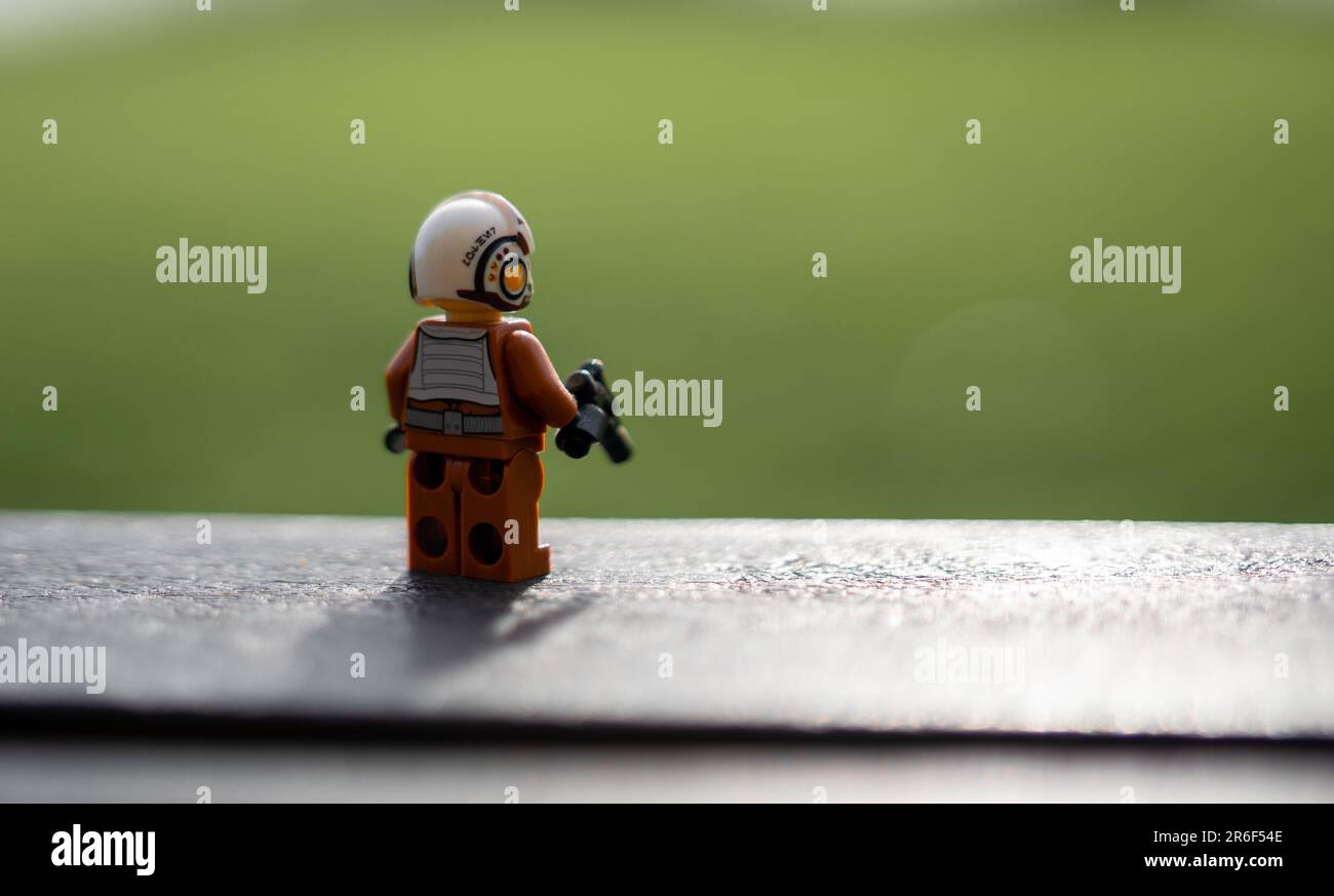 A small LEGO figurine wearing vest and yellow Alamy and white determined on ledge with bright confident Photo a expression a a standing - is Stock t-shirt