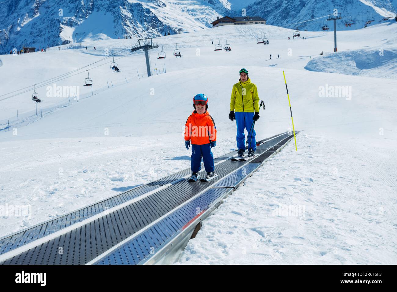 Little boy and a dad go up on the ski moving walkway Stock Photo