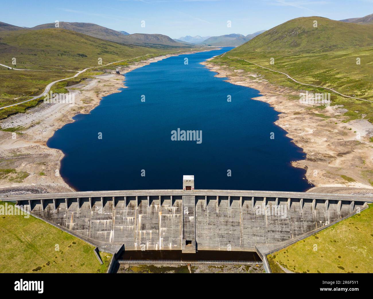 Garve, Scotland, UK. 9th June 2023. An aerial view of Glascarnoch Dam south of Ullapool. Prolonged drought conditions in the Scottish Highlands have led to low water levels in Glascarnoch reservoir near Garve.  Authorities have warned of possible water restrictions if the dry weather continues. Iain Masterton/Alamy Live News Stock Photo