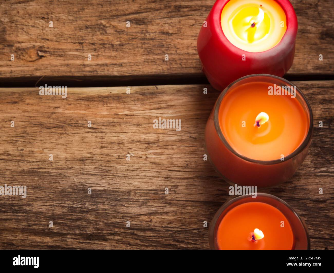 three candles sitting on top of a wooden table next to each other. . Stock Photo