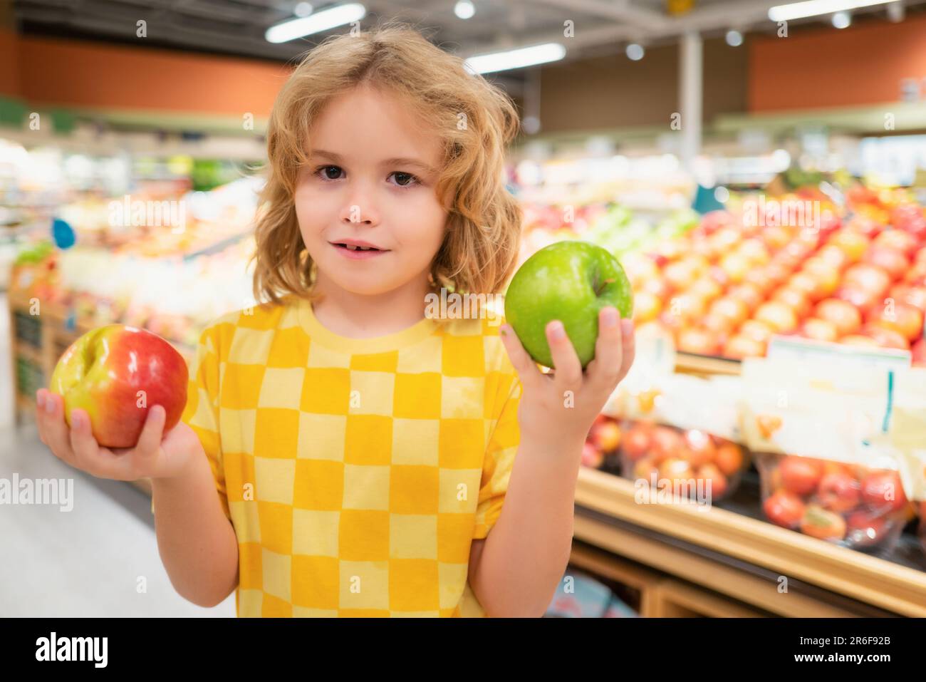 Child hold apple fruits at grocery store. Kid in a food store or a