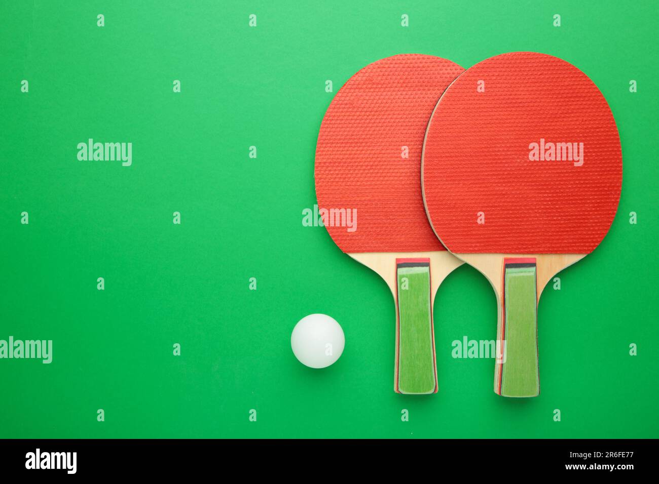 Ping pong rackets and ball on green background. Top view Stock Photo