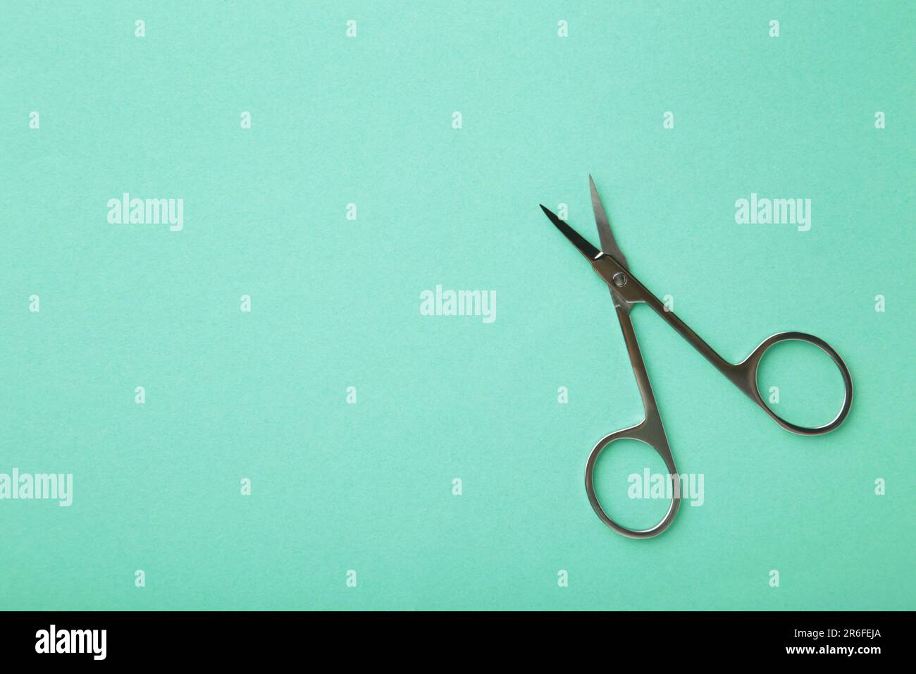 Small metal manicure scissors on mint background with copy space. Top view Stock Photo