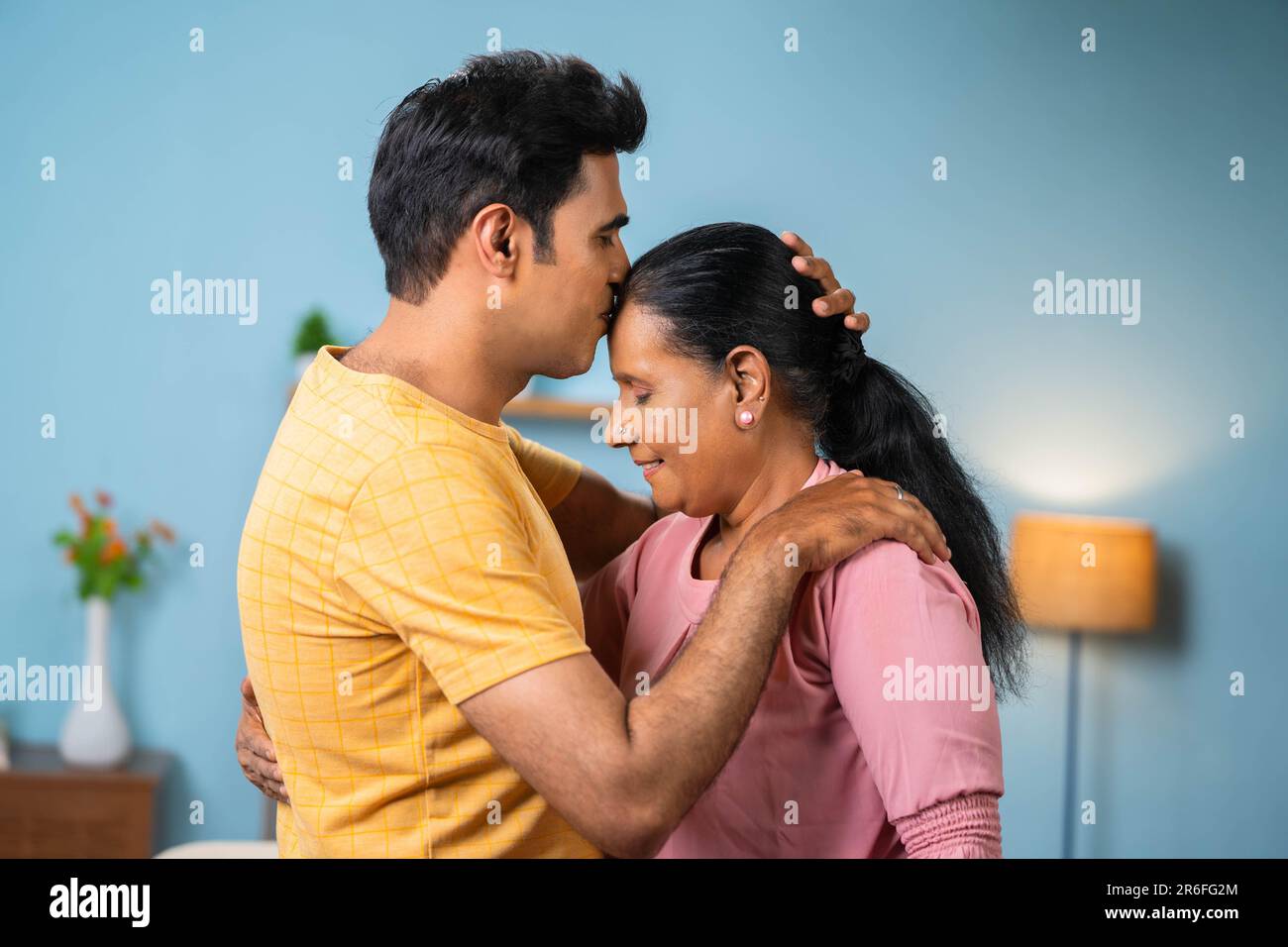 Happy indian adult son kissing to senior mother forehead at home - concept of love emotional, bonding and motherhood Stock Photo picture