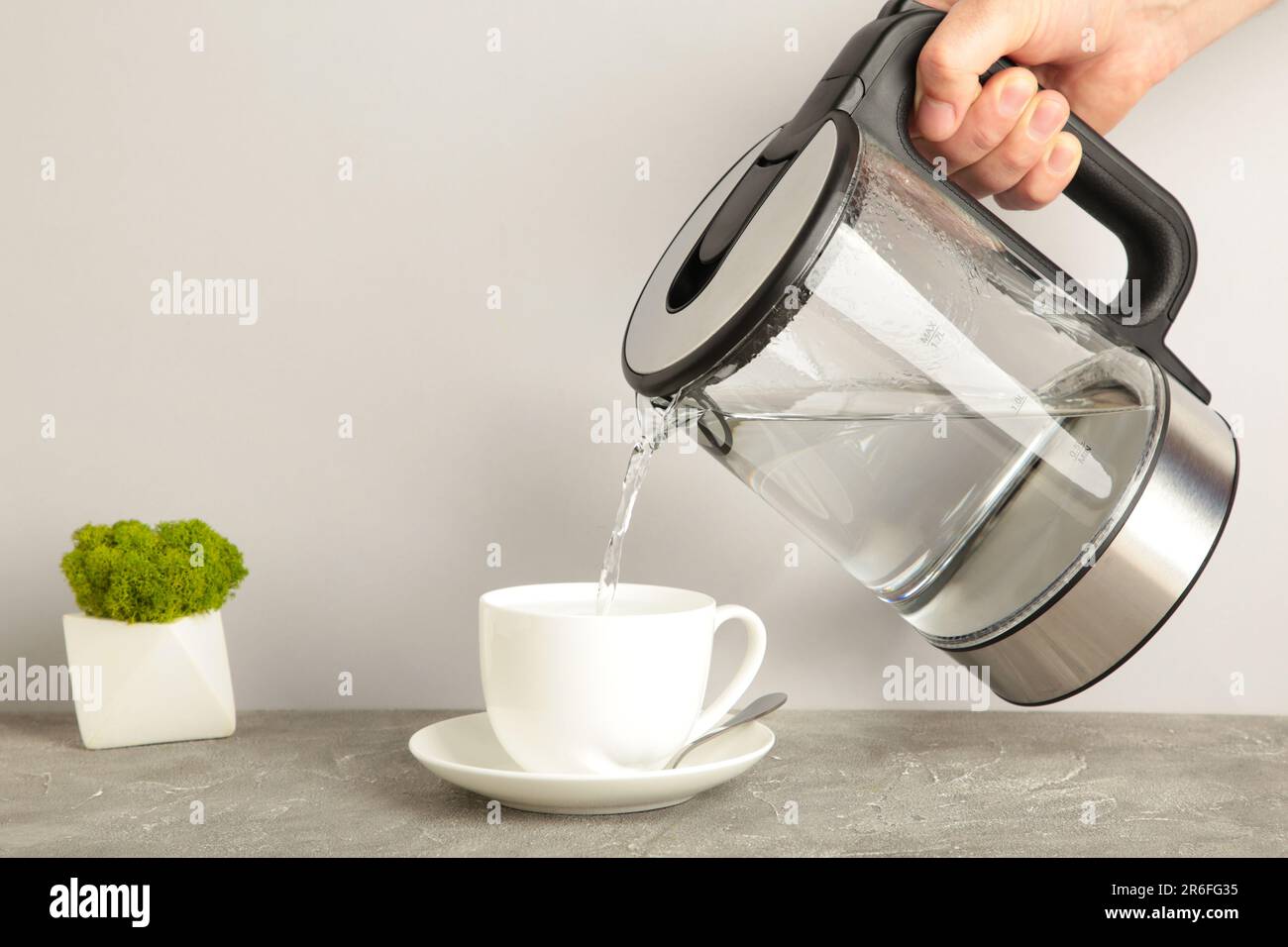 https://c8.alamy.com/comp/2R6FG35/kettle-pouring-boiling-water-into-a-cup-on-grey-background-top-view-2R6FG35.jpg