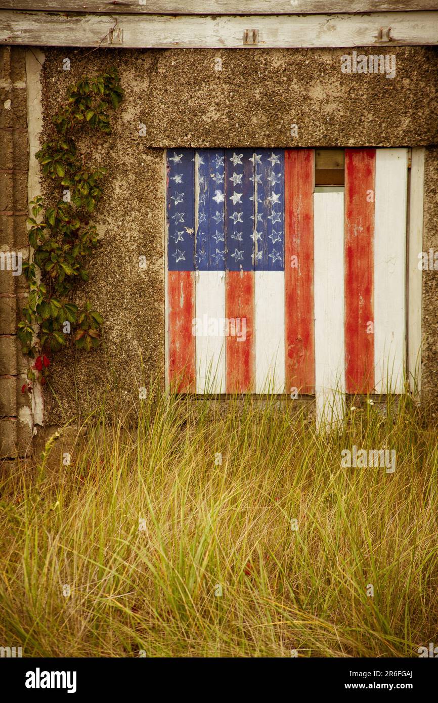 An aged and weathered shed with a vibrant American flag painted on the front door Stock Photo