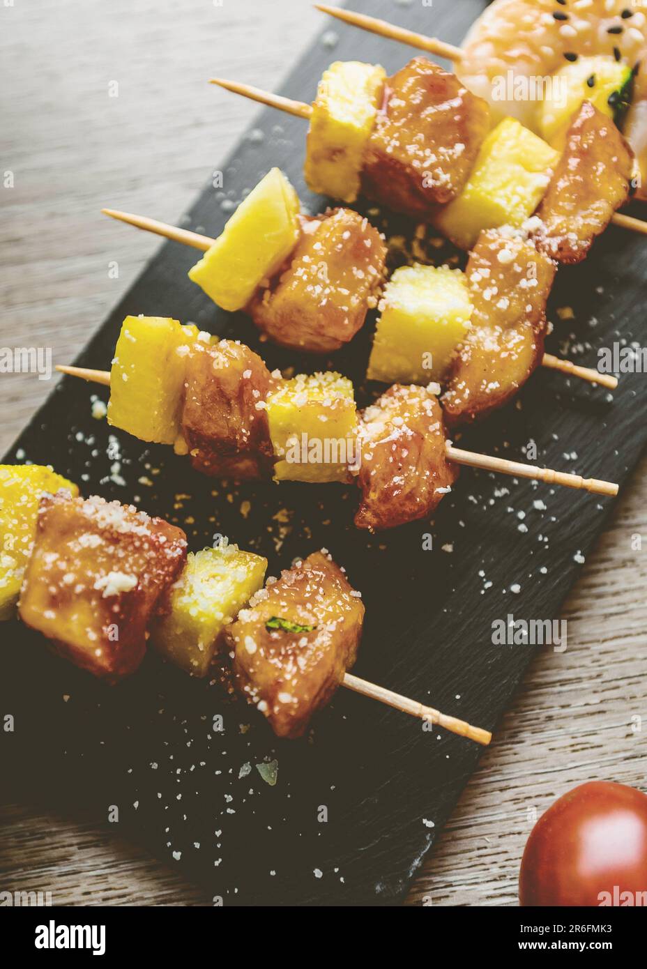 A succulent array of skewered meats and vegetables, arranged on a matte black board Stock Photo
