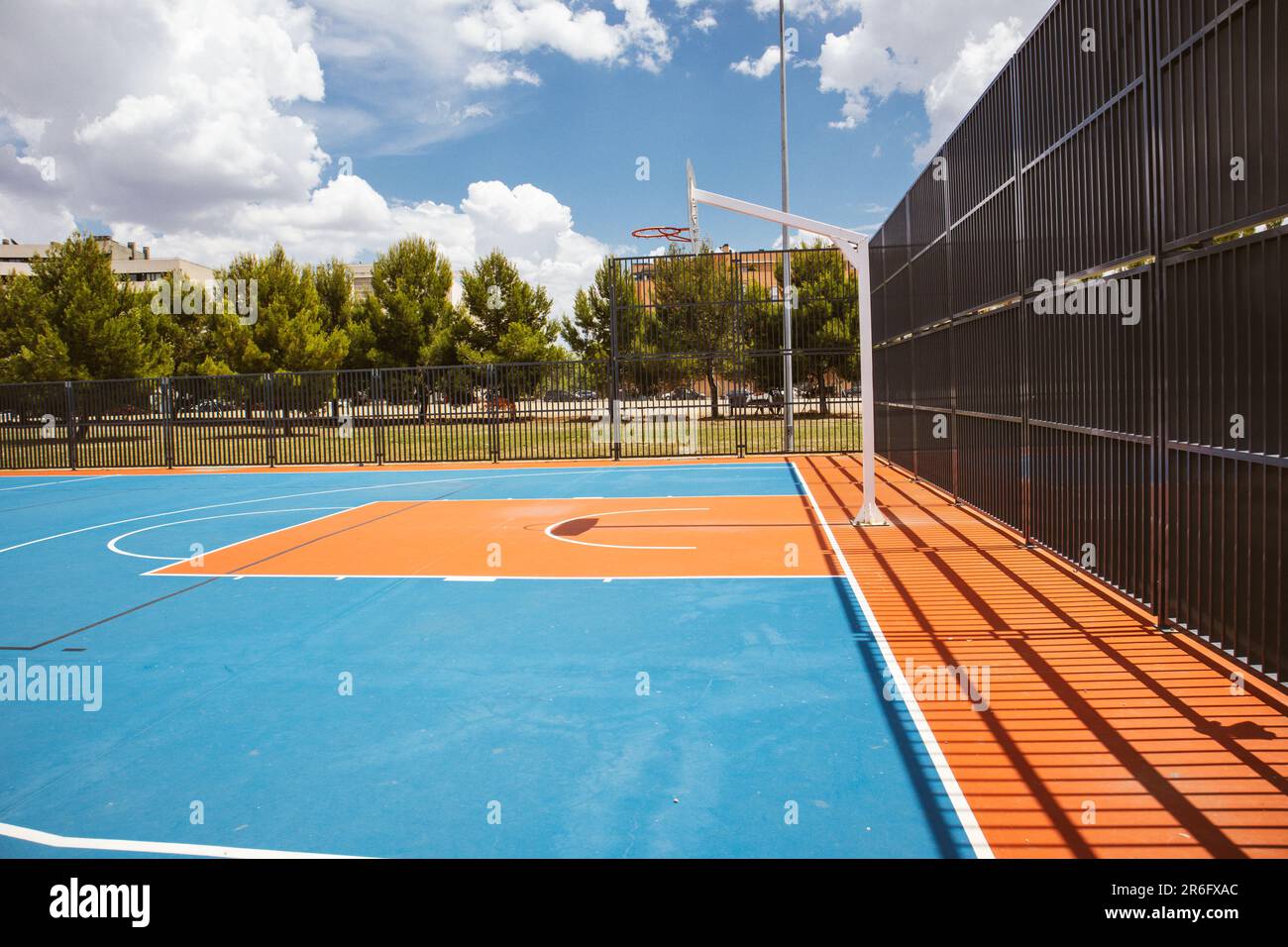 Empty outdoor basketball court in the garden and blue sky. Blue red basketball court for soccer