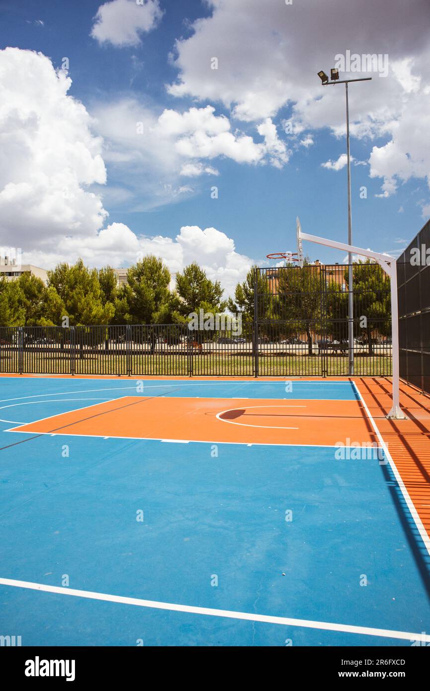 Empty outdoor basketball court in the garden and blue sky. Blue red basketball court for soccer