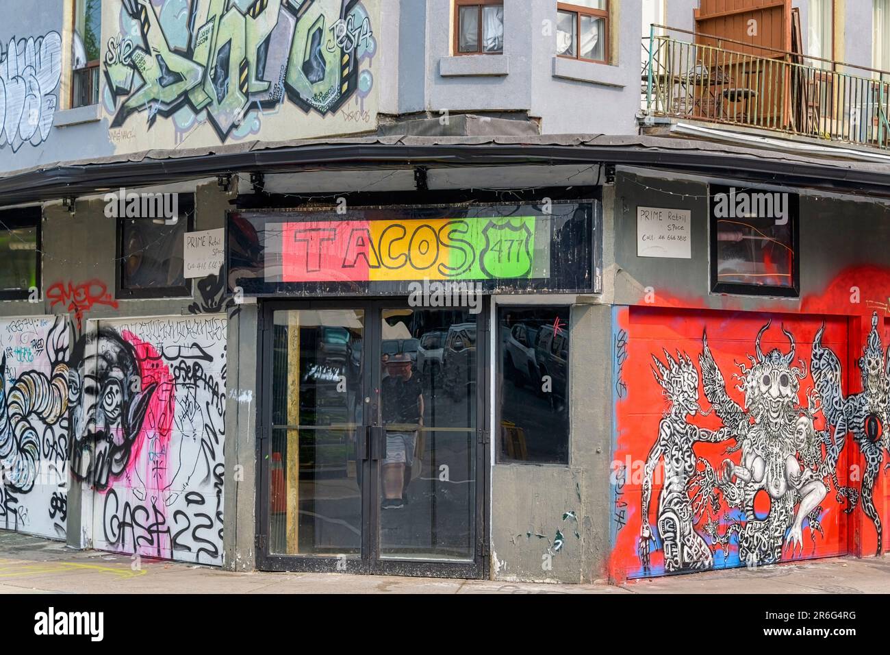 Toronto, Canada - June 4, 2023: Kensington Market. An old building with the signage 'TACOS 477'. Colorful witch monster art is on the building's wall. Stock Photo