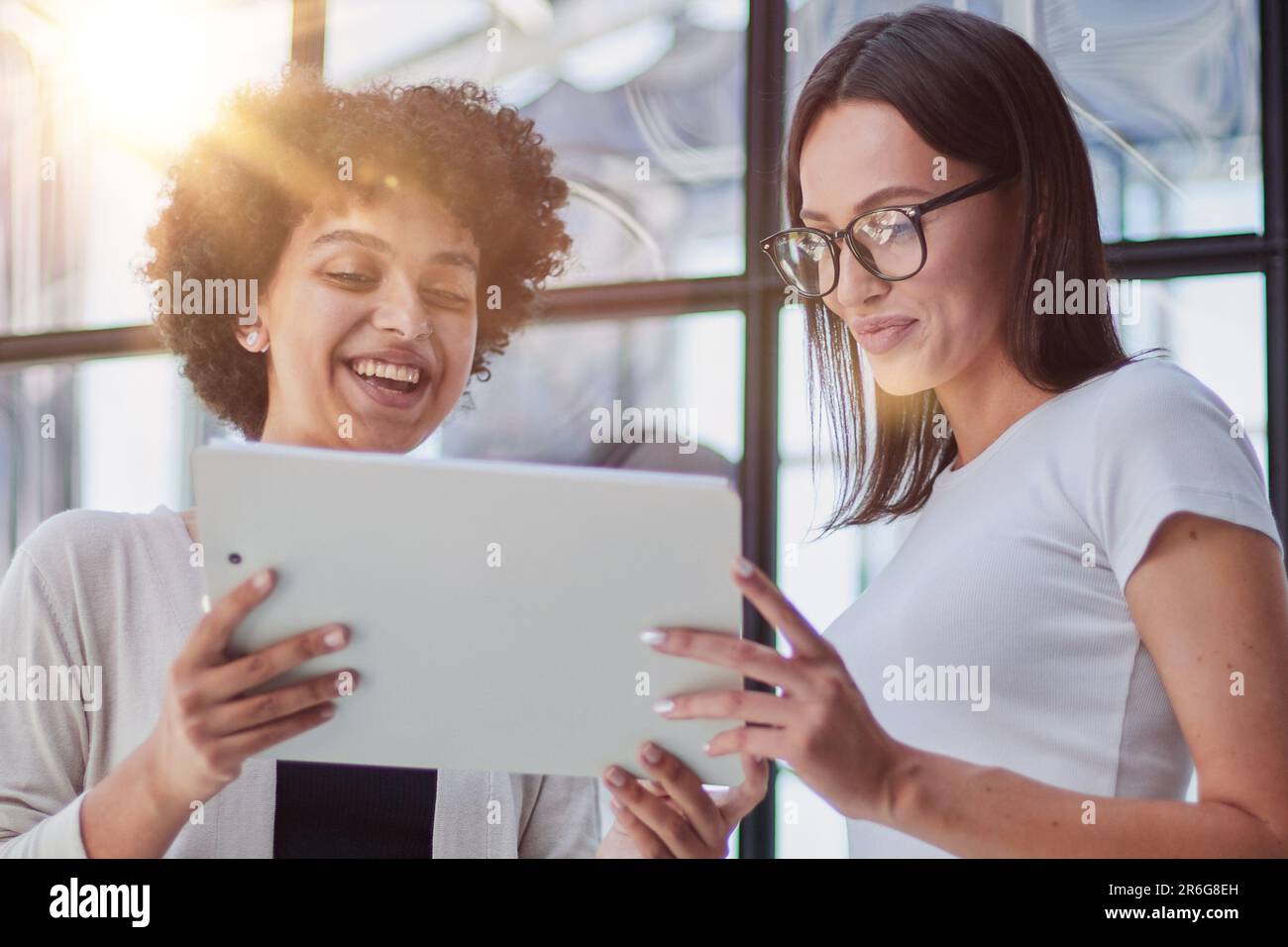 Cheerful female employees enjoying break. Two women in formal clothes sitting in office lounge, chatting and laughing Stock Photo