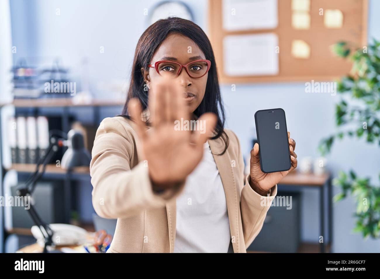 African young woman holding smartphone showing blank screen with open ...