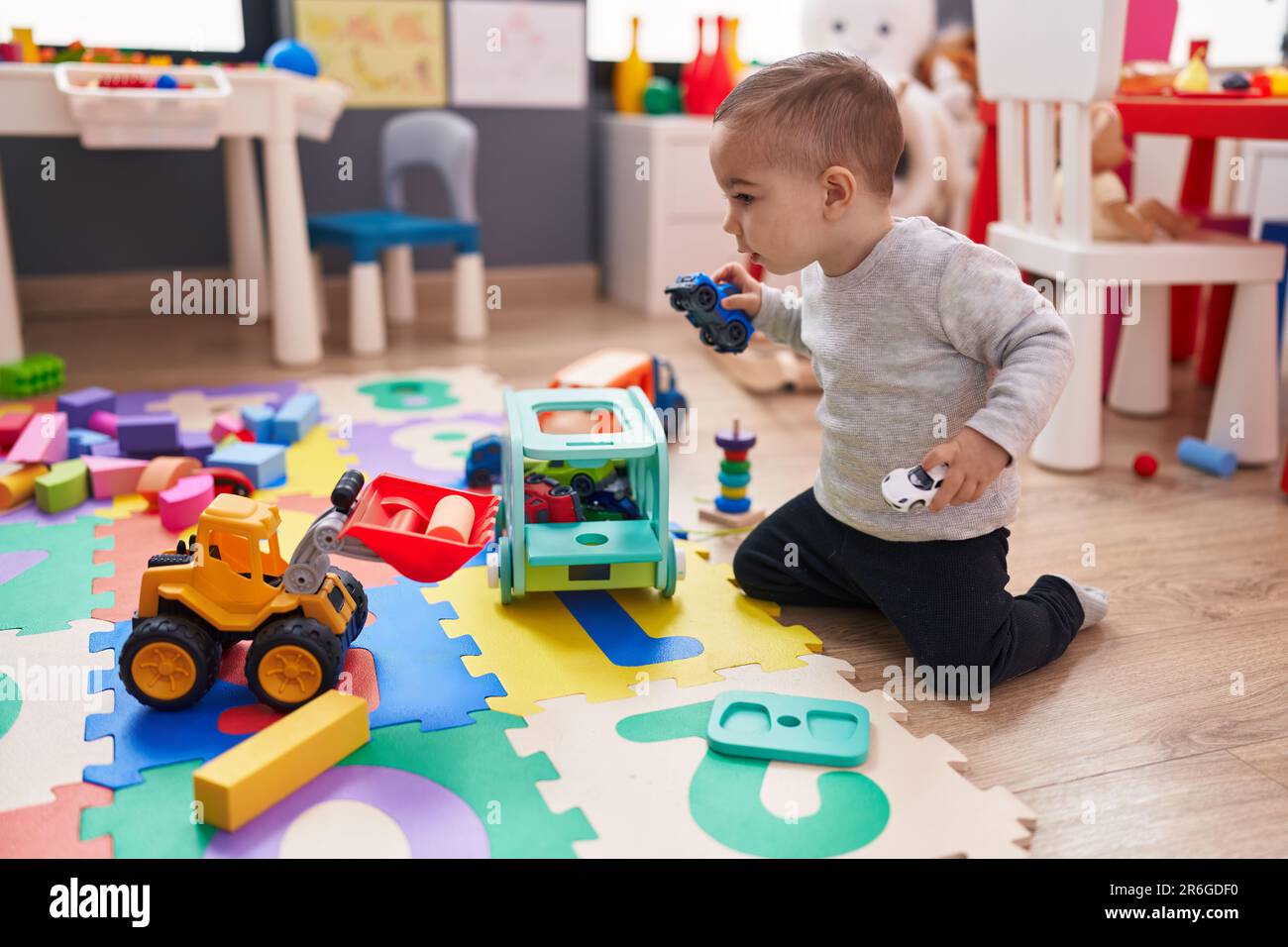 Adorable hispanic boy playing with car toy sitting on floor at ...