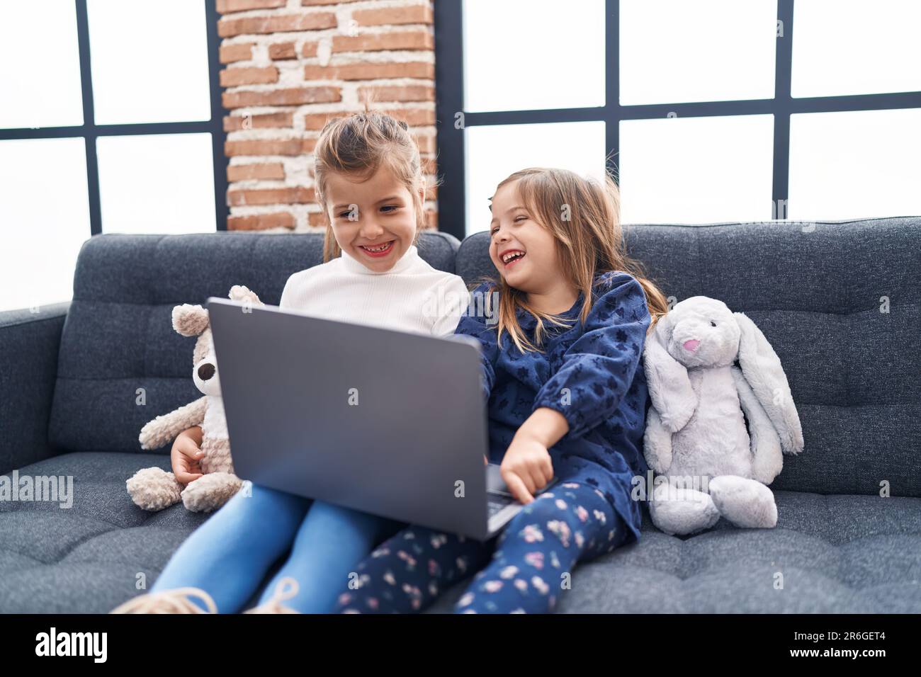 Adorable girls using laptop sitting on sofa at home Stock Photo - Alamy