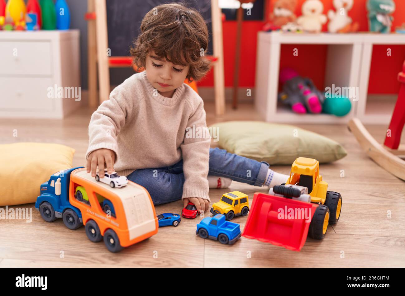 Adorable hispanic boy playing with car toy sitting on floor at ...