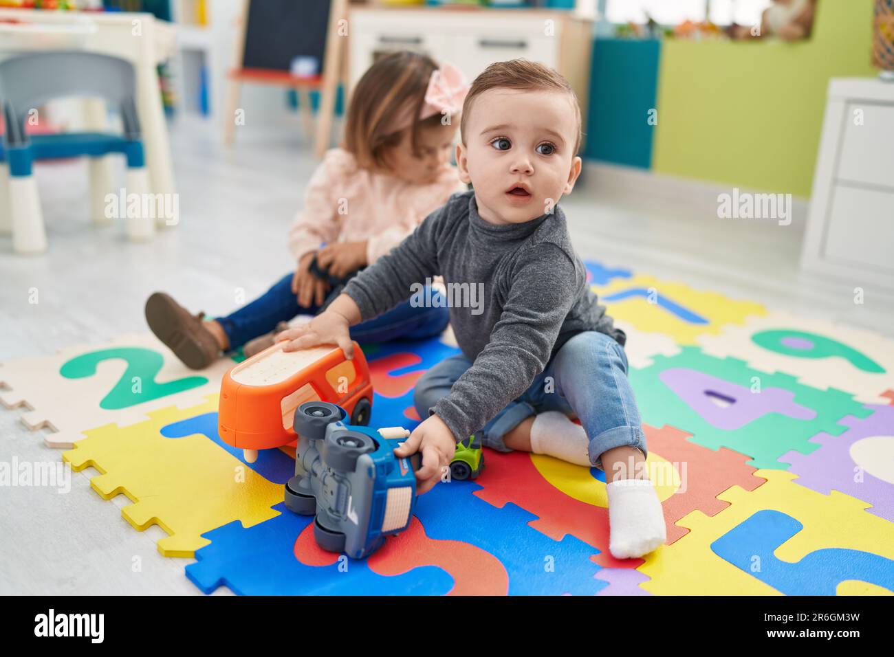 Adorable boy and girl playing with cars toy sitting on floor at ...
