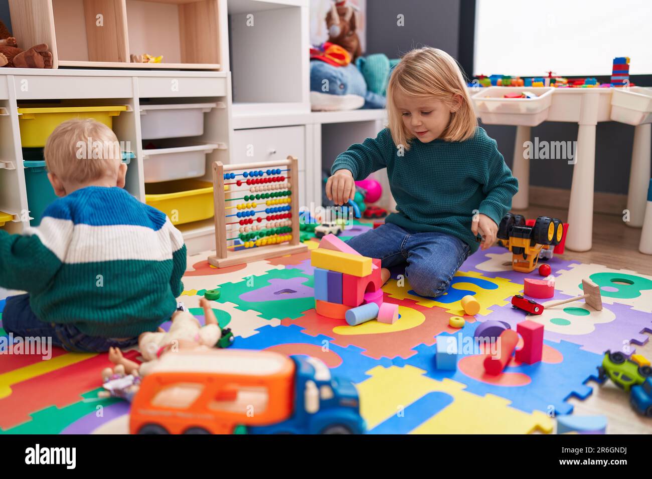 Adorable boy and girl playing with construction blocks sitting on floor
