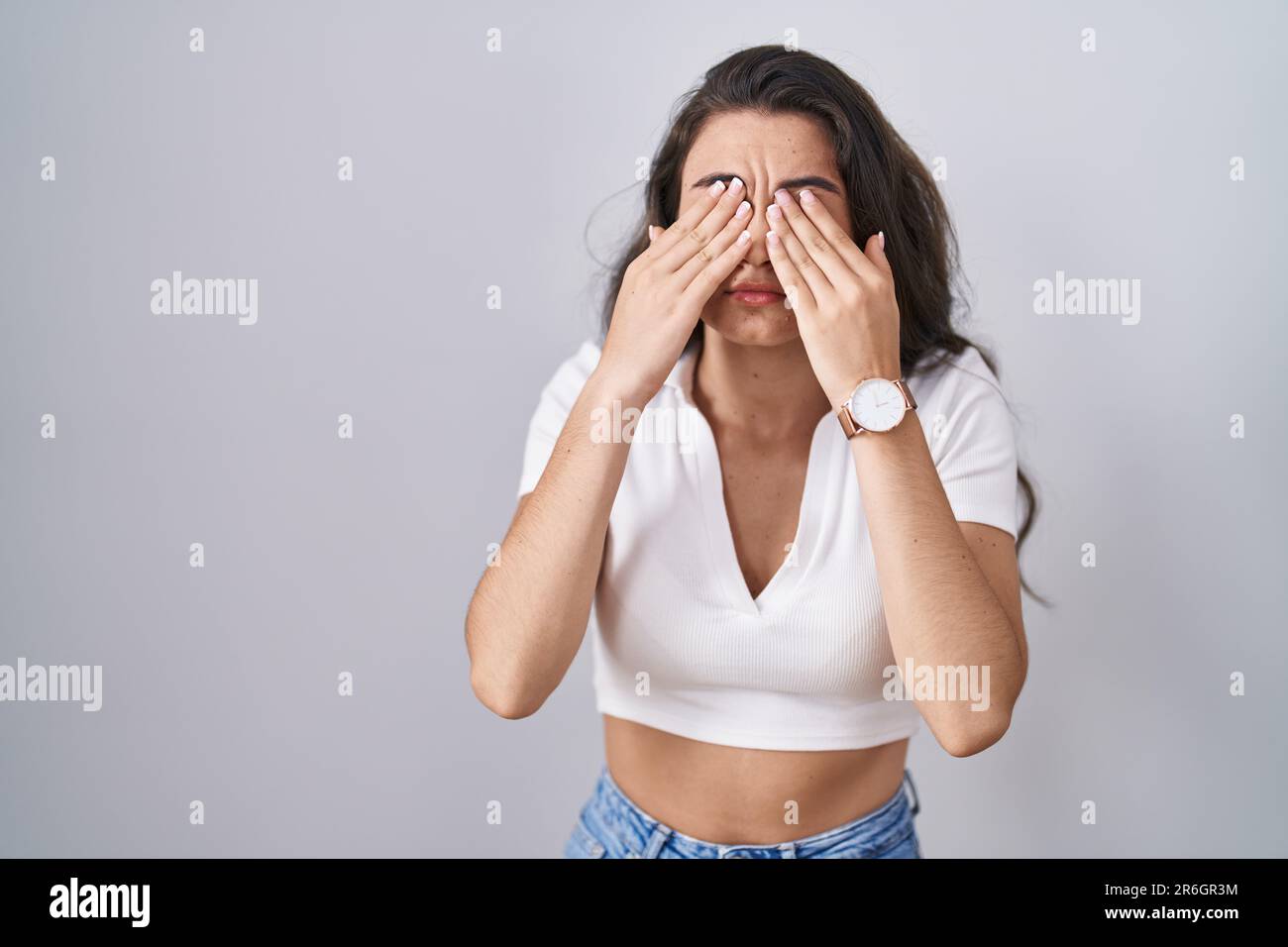 Young teenager girl standing over white background rubbing eyes for fatigue and headache, sleepy and tired expression. vision problem Stock Photo