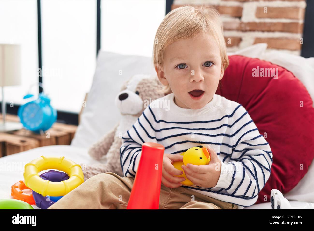 Adorable caucasian boy playing with hoops game holding duck toy sitting ...