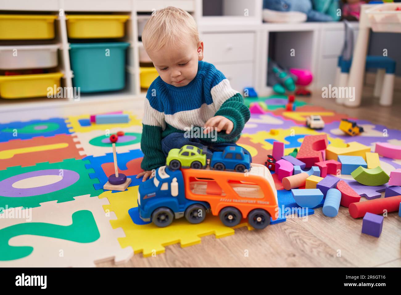Adorable caucasian boy playing with car toy sitting on floor at ...