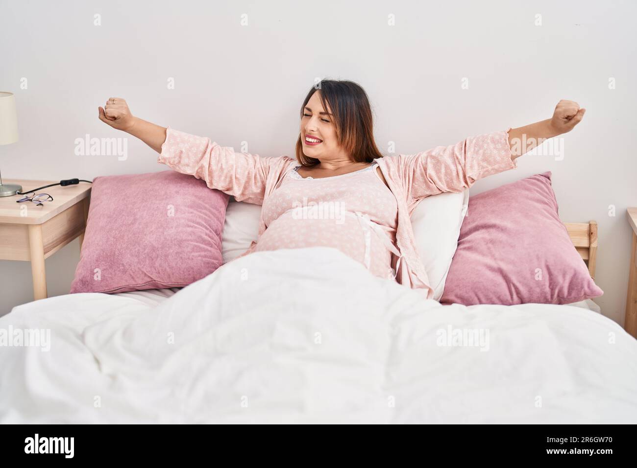 Young pregnant woman waking up stretching arms at bedroom Stock Photo Alamy