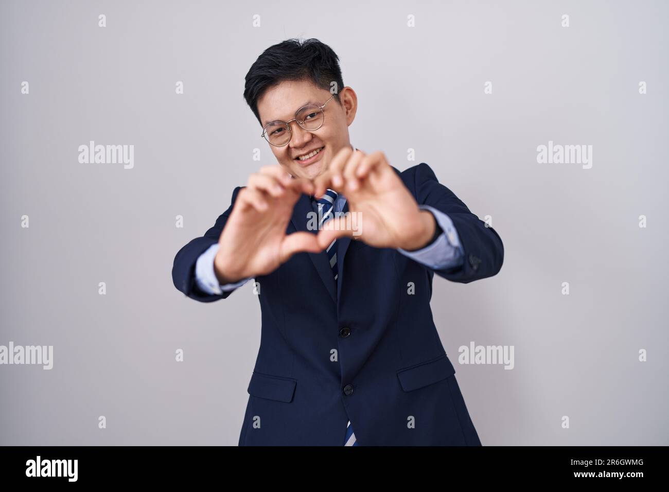 Young asian man wearing business suit and tie smiling in love doing ...