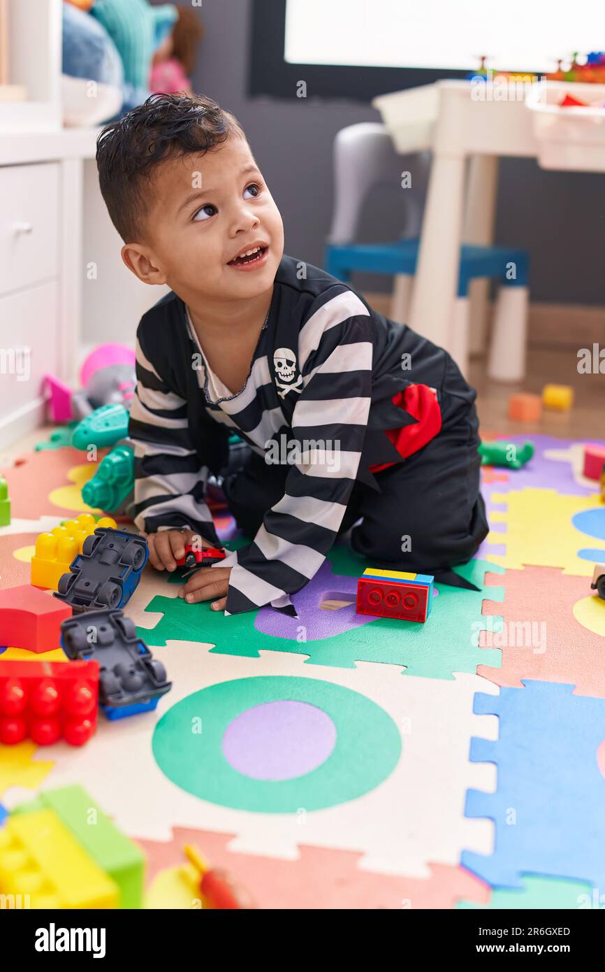 Adorable hispanic boy playing with car toy sitting on floor at ...