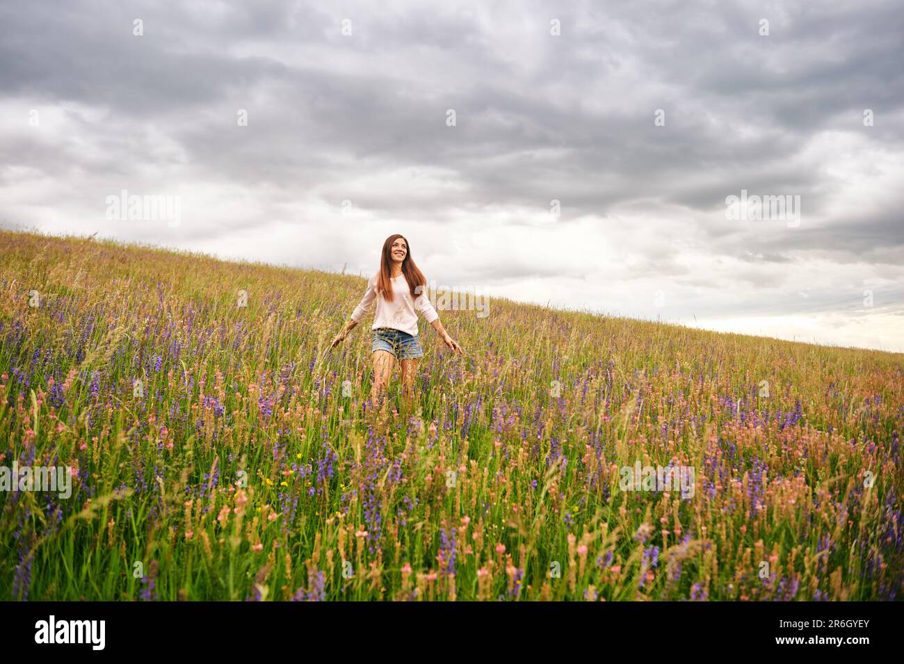 Young beautiful woman hiking in field with wildflowers Stock Photo